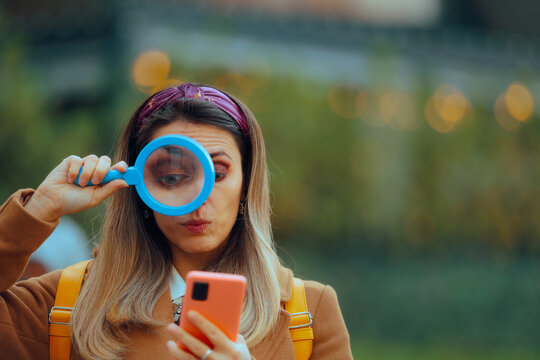 Woman Holding a Magnifier Checking her Smartphone. Person checking someone on social media investigating his character
