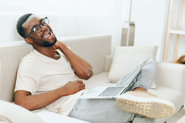 Smiling African American Freelancer Typing on a Laptop in a Modern Home Office, Engrossed in his...