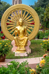 Dharma-Chakra statue of golden Buddha in wheel with flower park in Sarnath. Uttar Pradesh, Varanasi, India