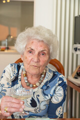 attractive elderly lady with a glass sparkling wine drinks a toast to her health