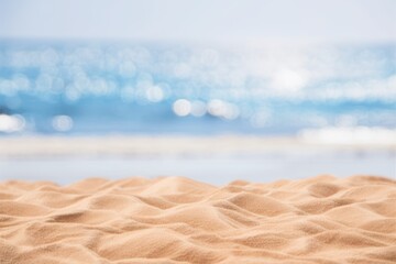 Soft focus image of sandy beach texture with shimmering ocean in the background