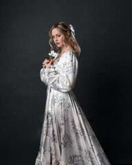close up portrait of beautiful blonde female model wearing romantic historical gown of white silk...