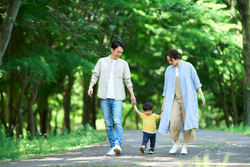 手を繋いで公園を歩く家族	
