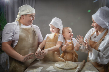 Cute oriental family with mother, father, daughter, son cooking in kitchen on Ramadan,...