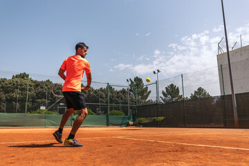 Man in sportswear playing tennis on a dirt tennis court