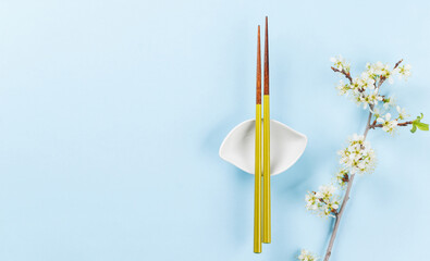 Table adorned with cherry blossom branch and chopsticks, epitomizing Japanese food culture