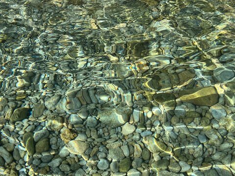 Sea pebbles gravel stones in transparent clear water.