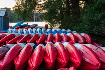 A collection of red and blue kayaks stacked upside down on the shore of Lady Bird Lake, Austin...