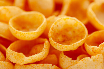 Close-up of crunchy, and salty puffed Cheese Snacks. Full frame, wallpaper. Front view.