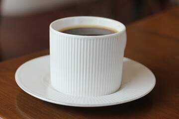 cup of coffee sits on plate in cafe (vintage style)