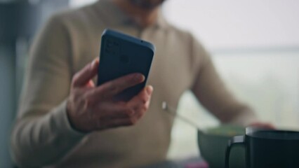 Eating man hand taking cellphone receiving notification at morning flat closeup - Powered by Adobe