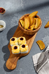 Baked sushi roll set with creamy topping alongside golden potato wedges, a fusion of flavors...