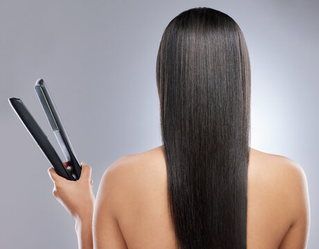 Girl, back and flat iron in studio for hair grooming or styling, haircare and beauty routine for wellness or keratin treatment. Woman, tool and isolated on white background for result, shine and glow
