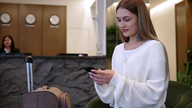 Stylish tripper texting in modern hotel lobby during evening check-in