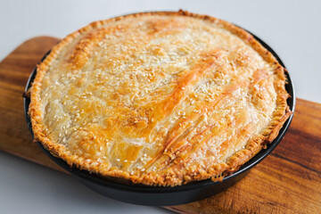 homemade round puff pastry pie in style of a sheperd's pie with sesame seeds topping just out of the oven