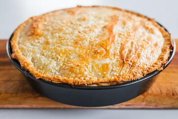 homemade round puff pastry pie in style of a sheperd's pie with sesame seeds topping just out of the oven
