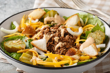 American Cheeseburger Salad with romaine lettuce, ground beef, pickles, cheddar cheese, onions and...