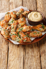 Chicken Parmesan Wings are oven-baked or air-fried and then coated in a buttery garlic parmesan sauce closeup on the plate on the table. Vertical