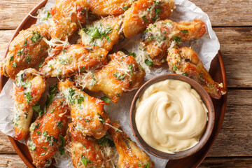 Parsley Garlic Parmesan chicken wings served with dipping sauce close-up in a plate on the table. Horizontal top view from above