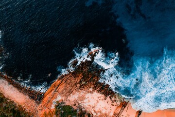 Aerial View of Turquoise Blue Ocean Beach With Crashing Waves and Red Dirt Sand and Rocks