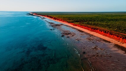 Aerial View of Turquoise Blue Ocean Beach With Crashing Waves and Red Dirt Sand and Rocks