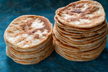 Flatbread lavash, chapati, naan, heap of tortilla on a blue background Homemade flatbread stacked.