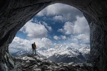 Wanderer in winterlichen Bergpanorama vor einer Höhle