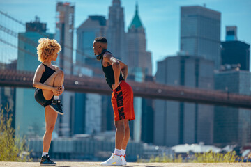 A man and a woman in sportswear stretching before a jog