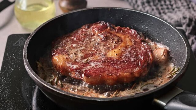 delicious juicy beef steak meat cooking on a pan with garlic and rosemary in melted butter. Process of making perfect steak at home