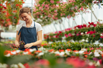 Woman caring for plants in greenhouse