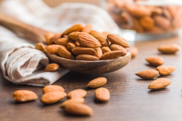 Peeled almond nuts in wooden scoop on wooden table.