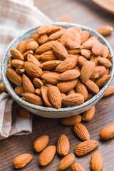 Peeled almond nuts in bowl on wooden table.