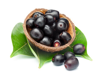A coconut shell filled with 'Indian blackberry' or Jamun (Syzygium cumini) fresh fruits with leaves. Isolated on a white background. Front view.