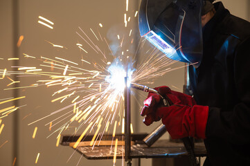 A man learns the craft of welding on a sample. 