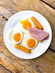Eggs with sausage in a plate on a wooden table