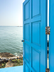 Blue wooden door open to the sea