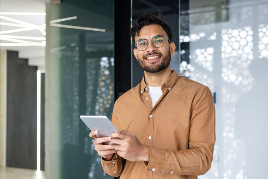 Smiling young professional using tablet in modern office environment