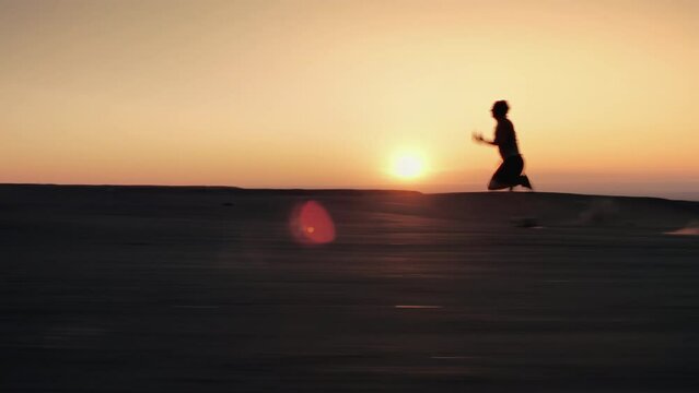 Silhouette of sporty runner is running very fast against sunset sky