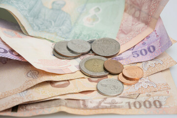 Thai baht consists of 20 bills, 100 bills, 500 bills, 1000 baht bills, and various coins placed together.