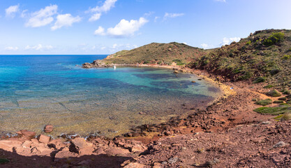 View of Cala Rotja, a little cove in the north of the island of Menorca, a stone and rock beach in a totally natural environment with little influx of tourists