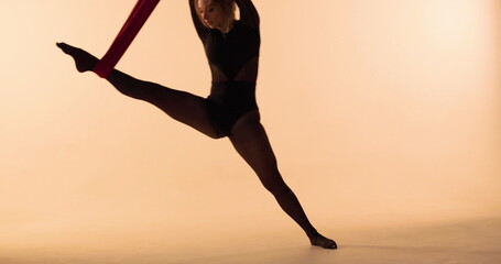 Aerial gymnast performs tricks on canvases in a studio setting against a white background in soft,...