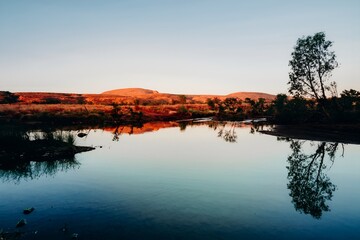 Mountainous Lake Waterhole Surrounded by Trees with Red Rock Cliffs Reflected in the Water at Sunset