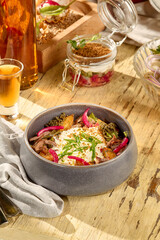 Hearty salad with roasted potatoes, shredded beef, onions, and smoked sour cream in a modern bowl