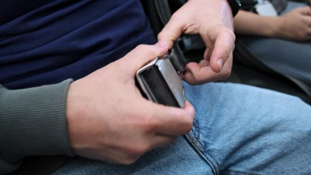 A man passenger unfastens the seatbelt on the airplane after takeoff and landing. A person unbuckled or unlocked buckle the seat belt on the plane. Concept of safe traveling by air. Safety rules. 4K