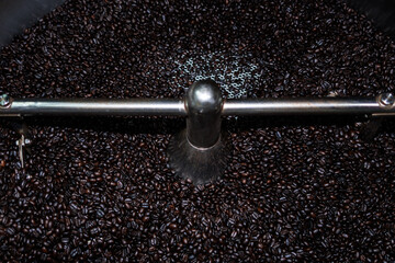 Close up of roasted coffee beans surface rotate in a spinning roaster mashine for background