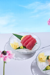 Tuna sashimi displayed on crushed ice, accented with surreal spring and summer flowers, a...