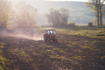 Tractor cultivating field at spring in sunset