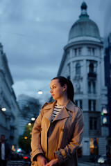 Portrait of beautiful caucasian woman wearing coat is walking by night Wien street.