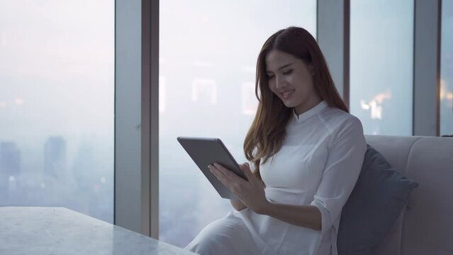 Portrait of Asian Vietnamese woman with dress and straw hat using mobile phone on Sky bar,on rooftop of hotel, building with city in Hanoi downtown skyline, urban city, Vietnam. People lifestyle.