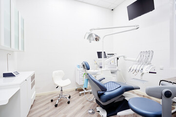 Dental equipment in dentist office in new modern stomatological clinic room. Background of dental chair and accessories used by dentists in blue and white.